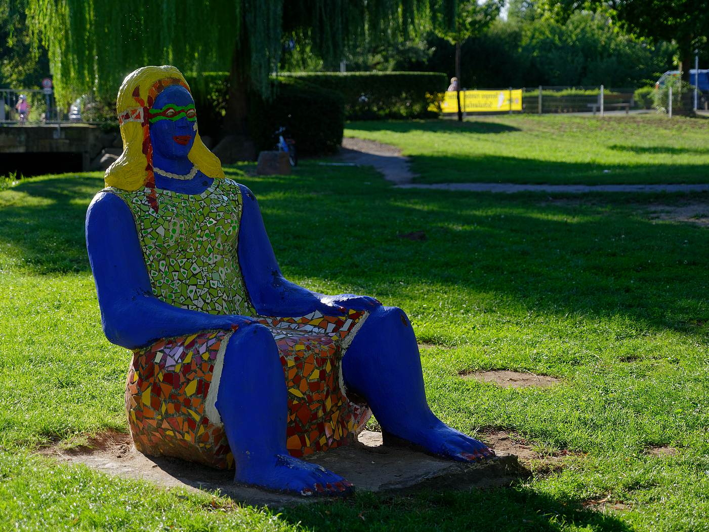 Blaue Stuhlriesin. Skulptur einer sitzenden Frau von Lou Heinrich.