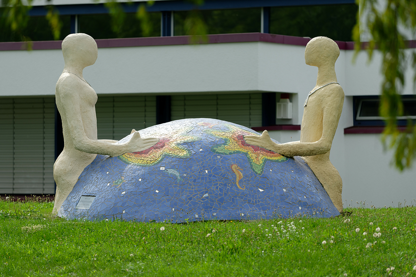 Erdball, der von zwei Figuren gehalten wird.